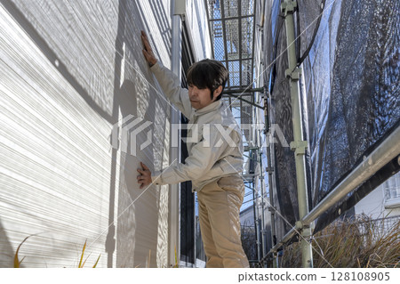 Repair work on the exterior walls of a detached house - On-site supervisor checking the progress of the work 128108905