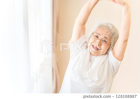 Senior woman relaxing and taking a deep breath in front of the curtains 128108987