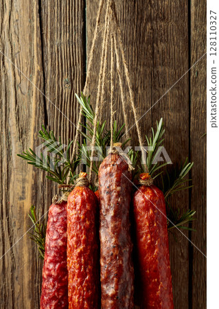 Smoked and dry cured sausages on a old wooden background. 128110327
