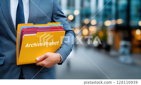 Businessman holds colorful folders labeled Archive Project in urban setting, symbolizing organization and efficiency 128110939
