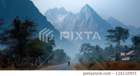 Motorbike rides on misty road surrounded by high mountains and lush greenery in Laos, creating serene atmosphere Motorbike rides on misty road surrounded by high mountains and lush greenery in Laos, creating serene atmosphere 128110955