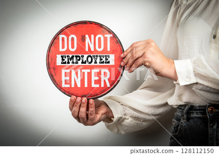 Employee Restriction Sign Held by Woman in Workplace or Office Environment 128112150