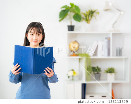 Girl reading a book in a room Girl reading a book in a room 128113839
