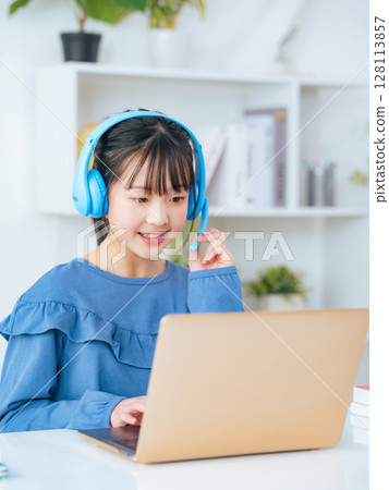 Girl wearing headphones and studying on a laptop Girl wearing headphones and studying on a laptop 128113857