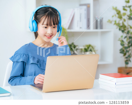 Girl wearing headphones and studying on a laptop 128113859