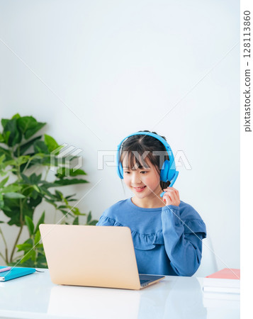 Girl wearing headphones and studying on a laptop 128113860