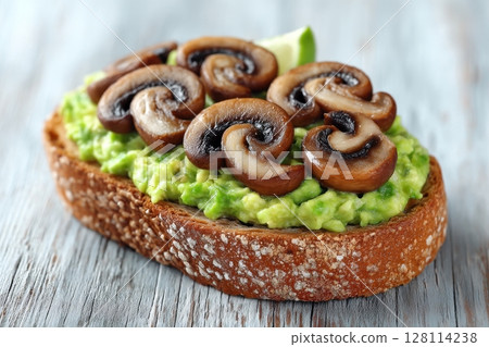 From a top view, overhead, a sandwich with avocado toast, mushrooms, and microgreens is showcased as a delectable option for breakfast or a snack 128114238