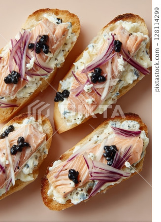 A selection of bruschetta featuring baguette, cream cheese, red caviar, pickled cheese, salted trout, and microgreens, all presented on a wooden board as a set of assorted appetizers 128114299
