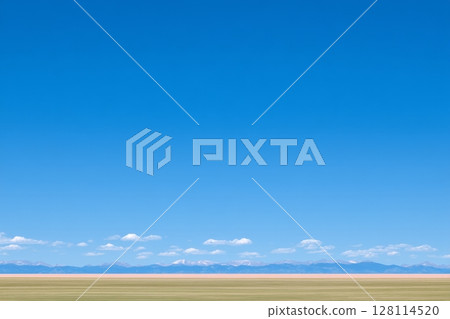 The stunning backdrop of Baikal, Russia, consists of a land road meandering over a hill with green and yellow dry grass, beneath a vibrant blue sky dotted with clouds, providing a spacious empty area 128114520
