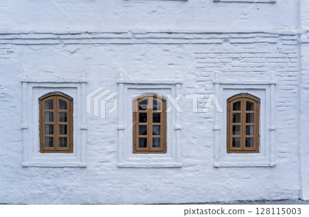 Three windows of the old 17 century building. Old stone wall with three windows Three windows of the old 17 century building. Old stone wall with three windows 128115003