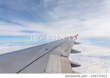 View from the airplane window at a beautiful cloudy sky and the airplane wing 128115021