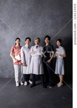 A team of medical workers standing in front of a black wall A team of medical workers standing in front of a black wall 128115435