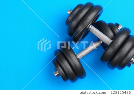 Fitness and exercise concepts are embodied by the various workout equipment, including metal weights and dumbbells, arranged on a blue exercise mat 128115486