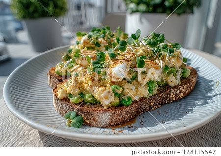 A white plate holding sandwiches with avocado and cressalate microgreens is set against a window background, representing a healthy diet and a vegetarian feed option 128115547