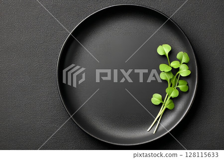 On a black background, a green plate holds a selection of fresh microgreen sprouts 128115633