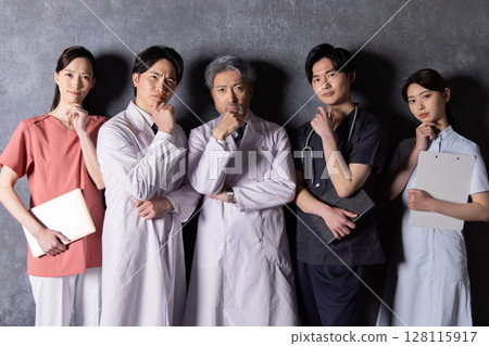 A team of medical workers thinking in front of a black wall 128115917