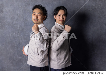 一名身穿工作服的男子微笑著舉起拳頭 128115937