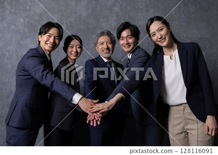 Business group standing in a circle with hands together 128116091