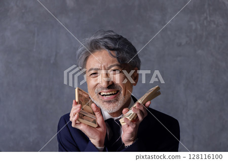 Smiling senior businessman holding a stack of bills 128116100