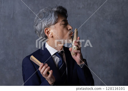 Smiling senior businessman holding a stack of bills Smiling senior businessman holding a stack of bills 128116101