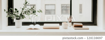 Home windowsill with lit candles and stacked books, minimalistic calm atmosphere 128116697