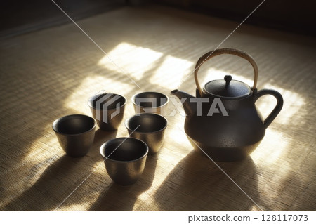 Elegant Japanese Tea Set on Tatami Mat with Natural Light Illuminating the Space 128117073