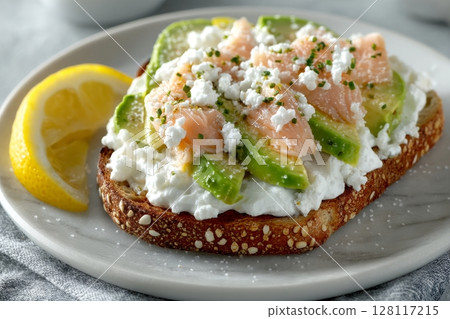 Dark rye bread toast accompanied by avocado, smoked salmon, and cucumber 128117215