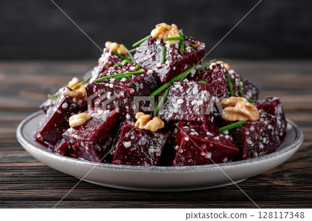 A rustic wooden table sets the scene for a salad of roasted beet, apples, walnuts, and microgreens, topped with scallions, and served in a blue pottery bowl with a golden spoon and homemade 128117348