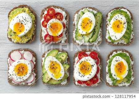 An assortment of nutritious vegetarian sandwiches is displayed on a white wooden surface from directly above 128117954