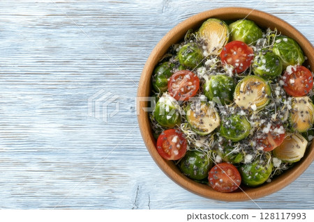 A nutritious vegan lunch option consisting of a salad with tomato, cucumber, red cabbage, carrot, onion, and microgreens, served on a wooden plate and viewed from above 128117993