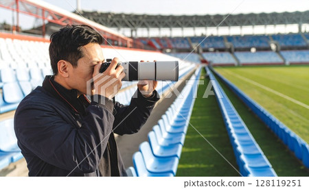一名男子在球場內手持長焦相機 一名男子在球場內手持長焦相機 128119251