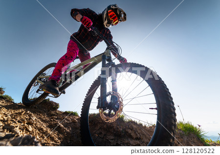 Mountain biker riding down a grassy slope. Enduro mountain bike. MTB against a mountain landscape 128120522