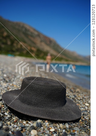 Straw Hat on Pebble Beach with Blurred Background Straw Hat on Pebble Beach with Blurred Background 128120713
