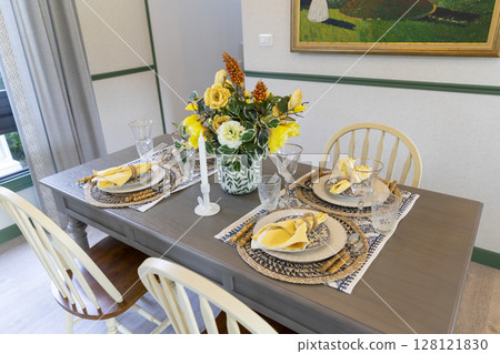 Artificial flowers on the dining table. Cottage plate setting with yellow handkerchief on wood table. Home decoration with beautiful flower. 128121830