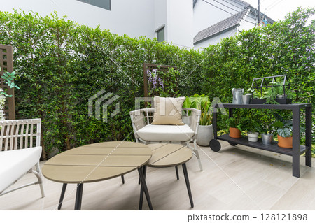 Outdoor veranda of house with brown wicker armchair and plants pots. Cozy space in patio or balcony with garland. Modern lounge outdoors in backyard. Outdoor veranda of house with brown wicker armchair and plants pots. Cozy space in patio or balcony with garland. Modern lounge outdoors in backyard. 128121898