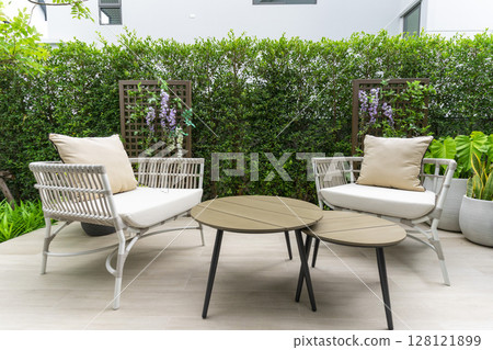 Outdoor veranda of house with brown wicker armchair and plants pots. Cozy space in patio or balcony with garland. Modern lounge outdoors in backyard. 128121899