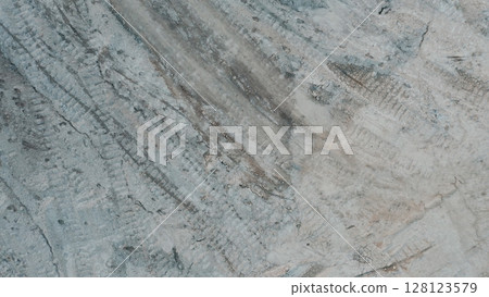 Top down view of dry cracked ground with visible tire tracks, showing drought-affected soil and erosion patterns in a barren landscape. Top down view of dry cracked ground with visible tire tracks, showing drought-affected soil and erosion patterns in a barren landscape. 128123579