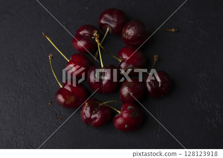 Rotten ripe cherries with mold and rotten sides on a black background. Seasonal fruits, harvest. Selective focus, close-up. 128123918
