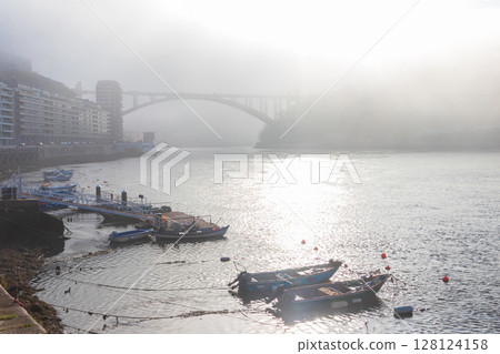View of Arrabida Bridge over the Douro River in the morning mist in Porto, Portugal 128124158