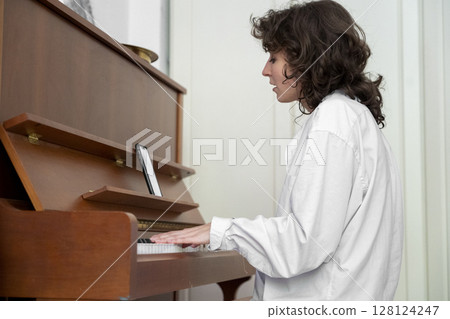 A person is beautifully playing the piano in a cozy indoor setting, exuding warmth A person is beautifully playing the piano in a cozy indoor setting, exuding warmth 128124247