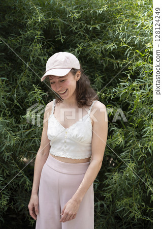 A Young Woman is Joyfully Smiling While Surrounded by Lush Greenery Dressed in Light Attire 128124249