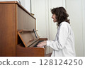 A person is energetically playing the piano while dressed in casual, comfortable attire 128124250