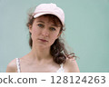 A Casual Portrait Featuring a Woman Wearing a Pink Cap Set Against a Solid and Simple Background 128124263