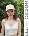A Smiling Young Woman Embracing the Beauty of Nature While Wearing a Stylish Cap 128124266