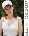 Stylish and Chic Summer Outfit Featuring a Cap Surrounded by a Natural Beautiful Setting 128124267