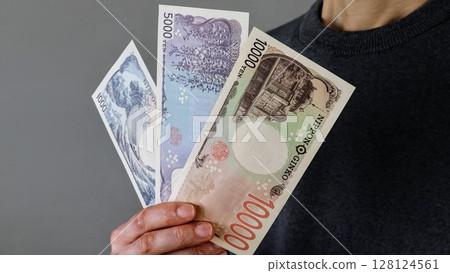 A person holding three new banknotes A person holding three new banknotes 128124561