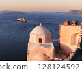 Sunrise at Santorini domed church and boats in the Aegean Sea 128124592