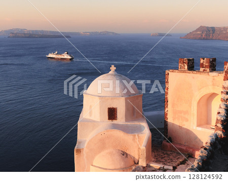 Sunrise at Santorini domed church and boats in the Aegean Sea 128124592
