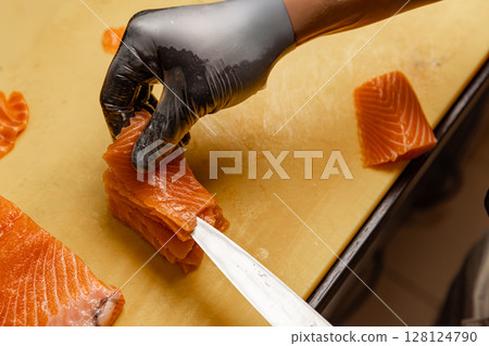 Chef arranging slices of fresh salmon 128124790