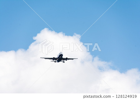 A passenger plane with its wheels out, preparing to land under bright sunlight seen from below, near a London airport 128124919